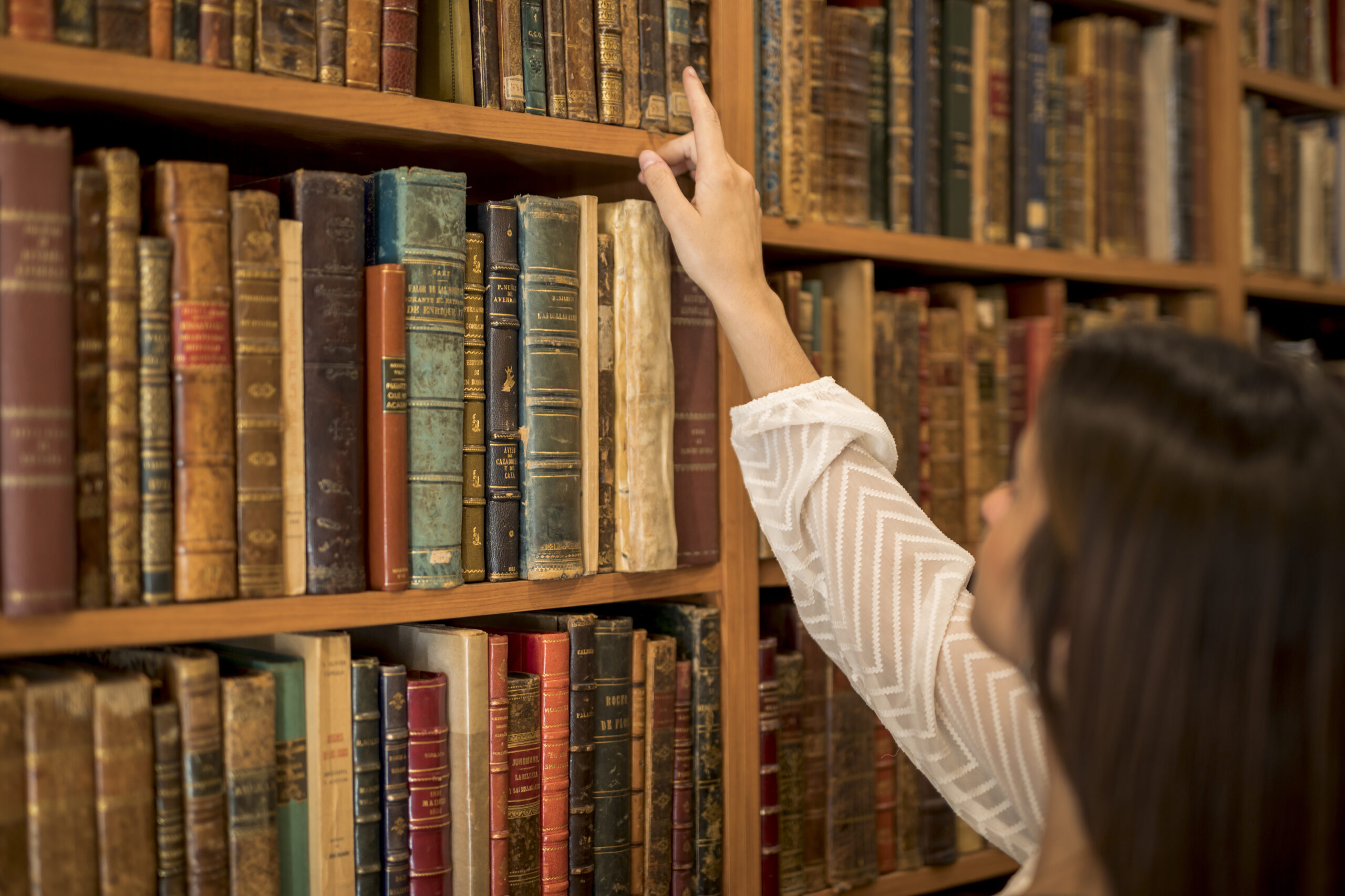 female-choosing-book-from-bookshelf-library